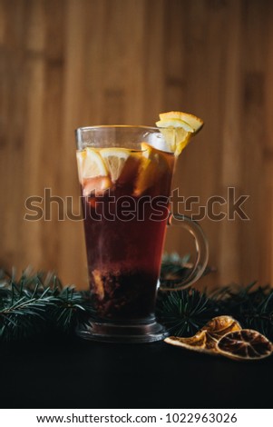 Traditional winter and autumn drinks. Christmas and Thanksgiving Cocktails. Mulled wine with orange, apple, rosemary, cinnamon and spices on a dark stone background, copy space, selective focus