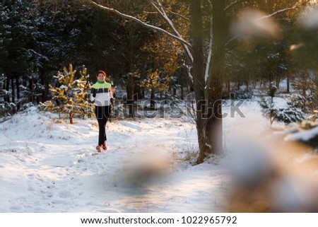 Photo of athlete girl in sneakers on morning run among trees