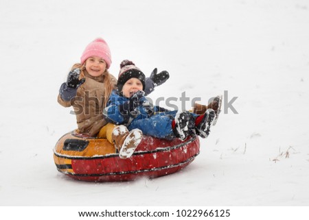 Picture of cheerful sister and brother riding tubing