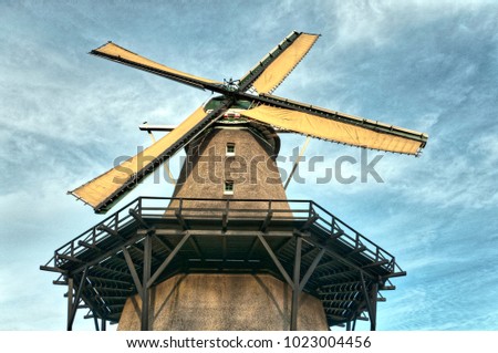 low angle view of a old Dutch windmill against a cloudy blue sky background