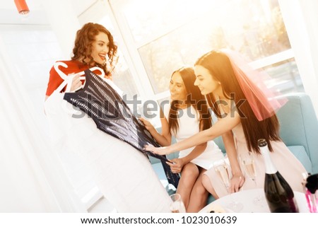 Girls have a great time at the hen-party. Three girls in dresses are having fun in a bright room. Bridesmaids and bride celebrating. Girls choose dresses for bridesmaids.