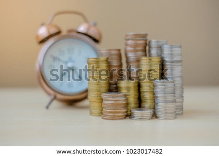 coins stack and retro alarm clock on wooden table in the morning sunlight. business, investment, retirement, finance and Money Saving for the future concepts