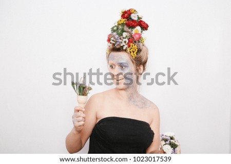 A young woman with flowers on her head and hands. Spring image with flowers. The girl and the blooming haircuts and brocade on her face.