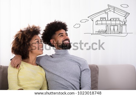 Happy Couple Sitting On Sofa Thinking Of Getting Their Own House Royalty-Free Stock Photo #1023018748