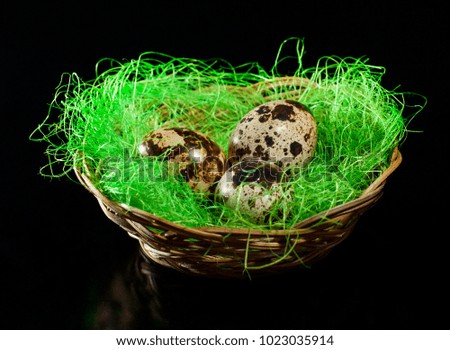 A wicker bowl with quail eggs on a dark background.
