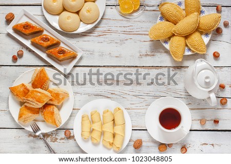 Traditional Azerbaijan holiday Novruz cookies baklava on white plate on the white background with nuts and shakarbura,gogal,sweetbread,tea,lemon,kata,mutaki,flat lay,top view,space for copy 