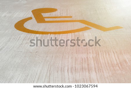 Yellow man in wheelchair. Disabled symbol on cement floor.This symbolizes parking space for the disabled with flare light and  copy space below.Concept is Everyone has their own space and hope
