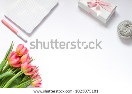 Minimalistic spring white desk flat lay with flowers and a gift.  Top view woman's or morher's day composition. Greeting card. Copy space