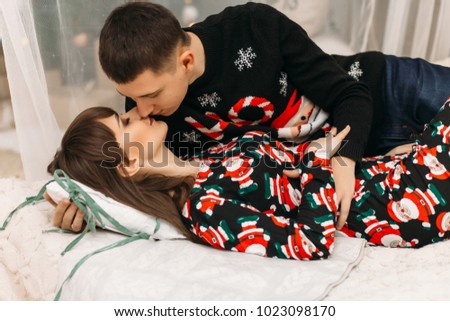 Man and woman rest on the bed in a room dressed for winter holidays