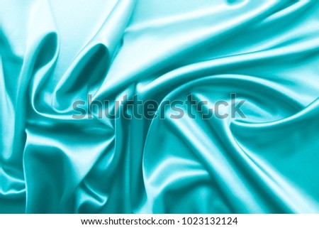 Smooth elegant turquoise silk or satin luxury cloth fabric texture, abstract background design.