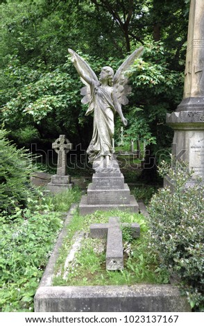 Highgate Cemetary, London, England.  Fairy tale memorial with its overgrown tombstones. Here a beautiful sculpture of an angel.