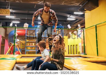 Happy young family with their little son jumping on a trampoline together at the entertainment centre Royalty-Free Stock Photo #1023138025