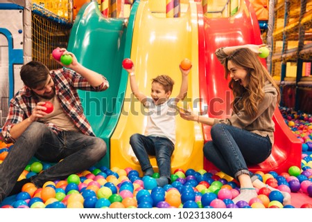 Excited little boy playing on a slide with his parents at entertainment centre Royalty-Free Stock Photo #1023138064