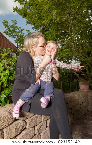 mother kissing her lovely daughter in the home garden