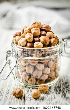 Hazelnuts in a jar on white wooden background. Selective focus, close up, space for text. 