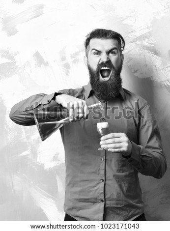 Bearded man, long beard. Brutal caucasian shouting hipster with moustache in brown shirt holding glass tube or flask and doing alcoholic red shot on colorful texture background