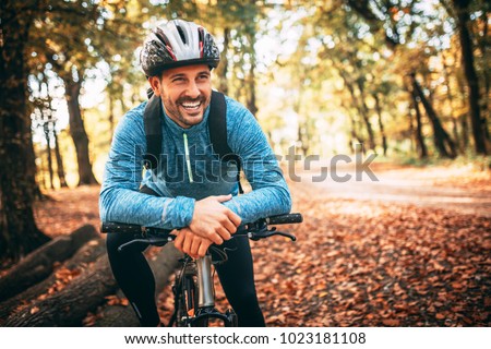 Professional mountain bike cyclist riding trail in forest, details of sports. Toothy smile. Royalty-Free Stock Photo #1023181108