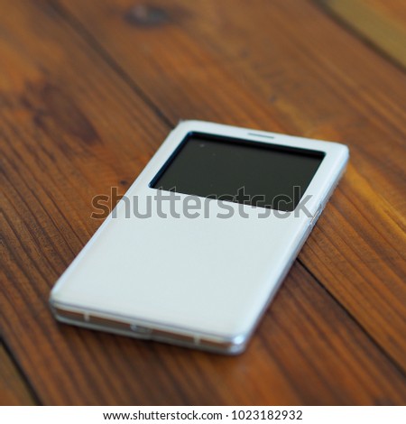 Mobile phone with white cover on table, vertical