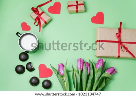 Valentine background with gift box, sweet, hearts and tulips on green table. Top view, flat lay