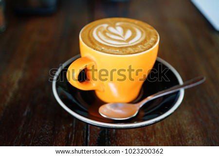 Orange coffee cup on a wooden table in a cafe. Summer terrace. Side view with copy space