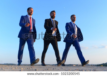 Businessmen with confident faces in formal suits and ties. Company leaders make step to success on blue sky background. Business, confidence and teamwork concept. Board of executives walk confidently