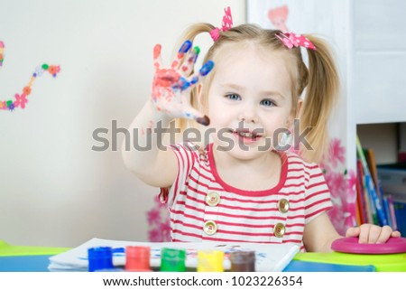 Little cute girl paints with fingers