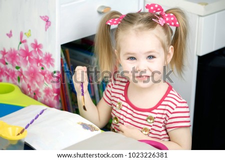 Little cute girl paints with brash
