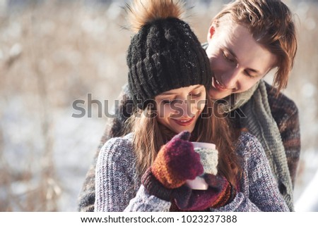 Photo of happy man and pretty woman with cups outdoor in winter. Winter holiday and vacation. Christmas couple of happy man and woman drink hot wine. Couple in love.