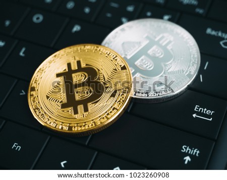 Shiny gold and silver bitcoin on black keyboard background, Enter button, Cryptocurrency concept