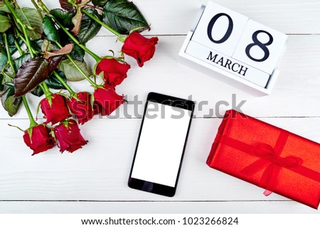 Red gift boxes, roses, cellphone with blank screen and cube calendar on white wooden background, copy space. Save the date, Womens Day, March 8. Greeting card. Top view, flat lay