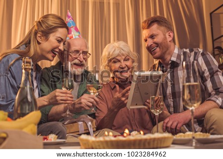 Outgoing woman with happy grandparents and glad husband discussing image in frame in room. Communication concept