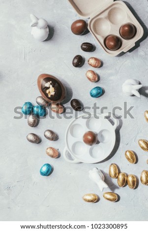 Chocolate Easter Eggs served on the grey stone board and decorated with ceramic easter bunnies. Top View