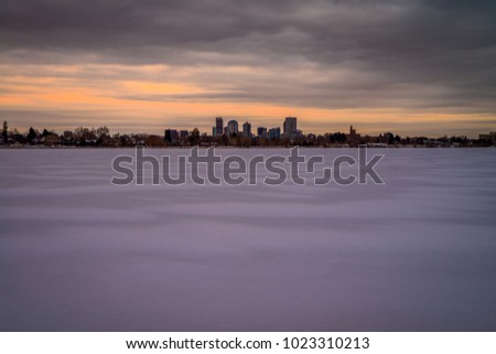The Denver skyline as seen from a frozen Sloan Lake during sunset.