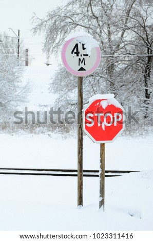 Stop. Red road sign is located on the motorway crossing the railway line in winter season