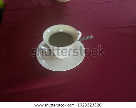 White coffee cup on the table covered with red cloth.
