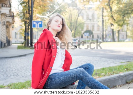 Portrait of beautiful long-haired girl in casual outfit leaning on fence in sunny park. Spring sunny concept. Cute teenage girl. 