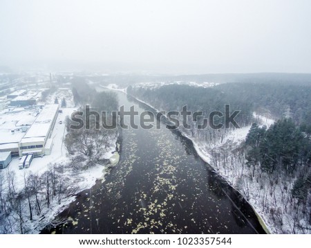 It is snowing in Vilnius, Lithuania, aerial top view of Neris river in winter