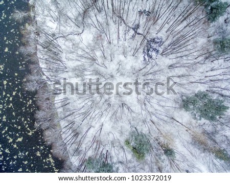 Aerial top view of winter forest and ice drift on the river