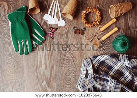 Spring gardener table top view with tools, gloves, peat pots and garden labels on brown wooden background. Flat lay composition, seasonal preparations for sawing seeds