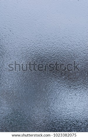 Texture of frozen drops on glass. Abstract winter textured background.