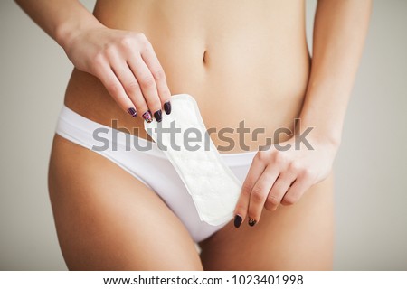 Female Hygiene. Closeup Of Beautiful Woman With Fit Slim Body In White Underwear Holding Sanitary Towel, Panty Liner In Hands. Girl Holding Clean Period Pad, Feminine Intimate Product. High Resolution