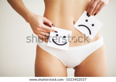 Woman Health Problem. Closeup Of Female With Fit Slim Body In Panties Holding White Card With Sad Smiley Face Near Her Stomach. Digestive Disorders, Period Pain, Health Issues Concept. High Resolution