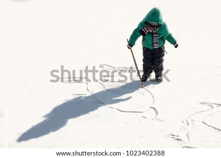 Happy boys in colorful winter clothes drawing picture on ice and snow. Glasses for skiing, snowboarding and sledging. A child is playing outdoors in the snow. Outdoor fun for winter holidays