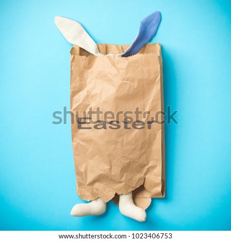 Easter bunny in a paper bag with the inscription Easter. Blue background. Space for text. 