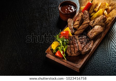 Assorted delicious grilled meat with vegetable. Mixed grilled bbq meat with vegetables. Mixed grilled meat on wooden platter. Copyspace. Royalty-Free Stock Photo #1023416758