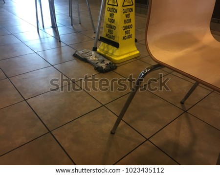 Empty restaurant with a mop leaning on a caution of wet flooring cone. 