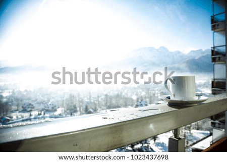 hot coffee on a handrail in a white mug surrounded by beautiful winter mountains