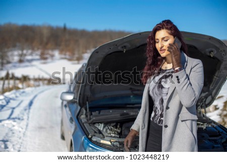Redhead girl talking on the phone. Broken car in background. 