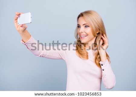 Close up portrait of cheerful delightful lovely cute beautiful charming woman making a self portrait using her modern smart mobile phone, isolated on grey background
