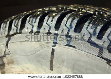 Melting snow on a studded car wheel. The arrival of spring. Car tire. Close-up.